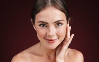 Woman with smooth, radiant skin and even complexion touching her face gently, demonstrating the improved skin texture and luminous results achievable with MOXI laser treatment
